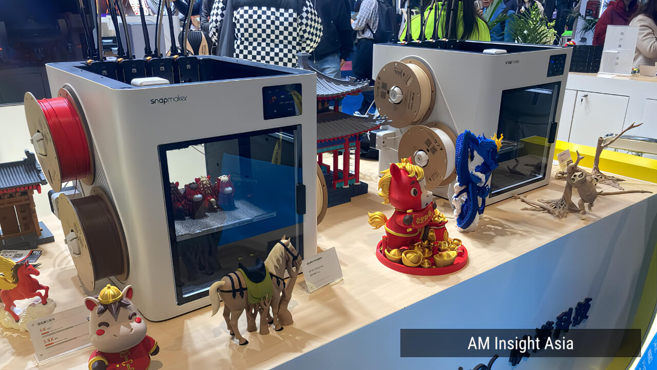 Snapmaker U1 on the show floor, with multicolor printed models demonstrating the SnapSwap™ toolchanging system.