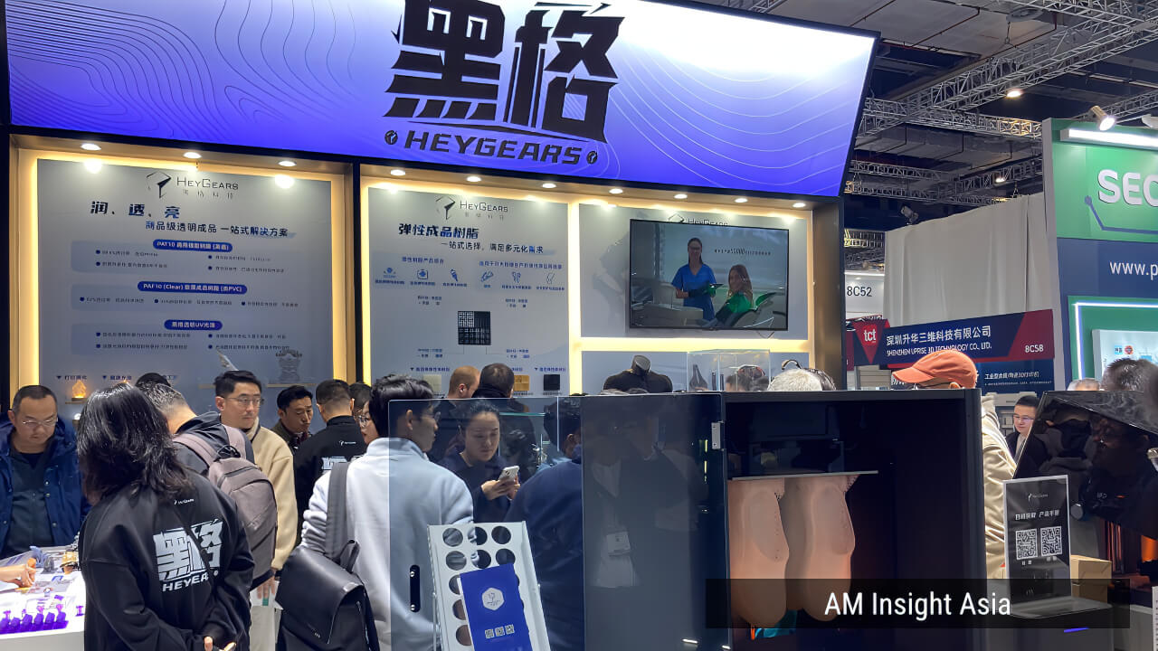 HEYGEARS booth at TCT Asia 2026 — transparent and elastic resin lineups on display, large-format printer running live.