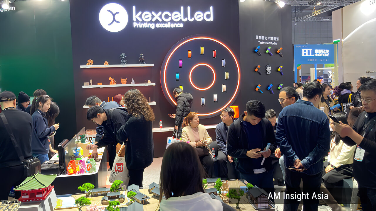 kexcelled booth at TCT Asia 2026 — colorful filament spools, printed figurines, and the architectural diorama drawing visitors in.