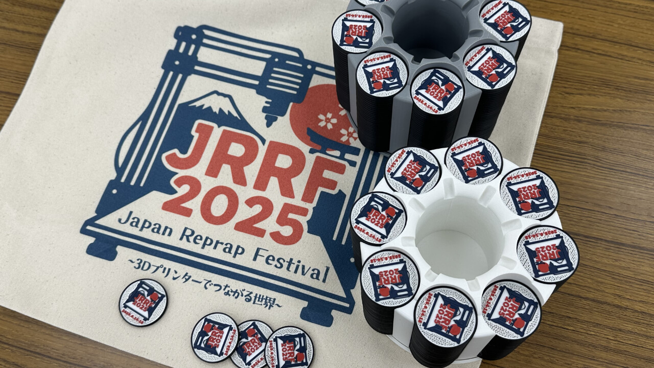 The official JRRF2025 tote bag alongside MakerChips, collectible badges 3D-printed by the organizers and exchanged between participants throughout the event.