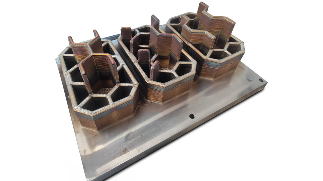Three snow pads produced simultaneously in a single Meltio M600 print cycle. Layer lines are clearly visible.