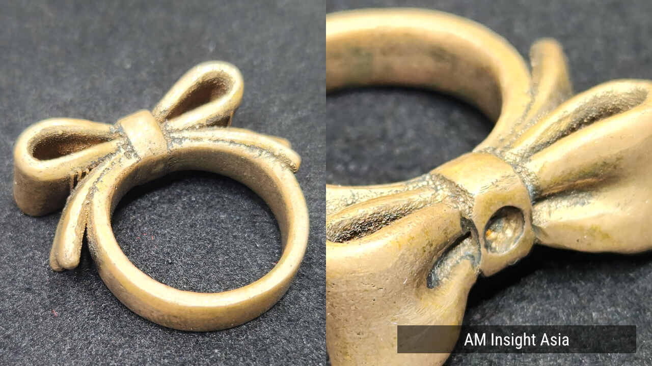A bow-shaped ring in copper alloy, with a close-up of the knot (right). Besides stainless steel, SnowPod also works with copper alloys. | Photo: AM Insight Asia